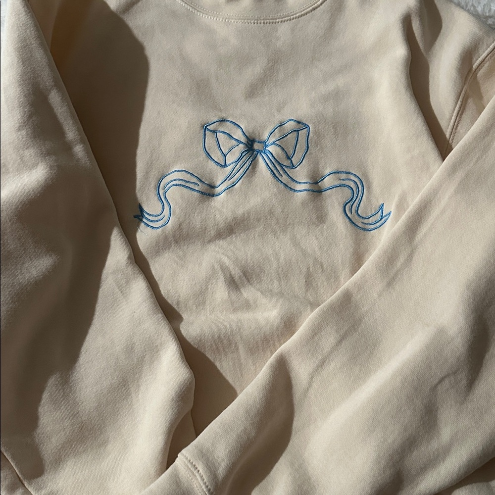 Light yellow / cream crewneck with light, blue bow size medium
